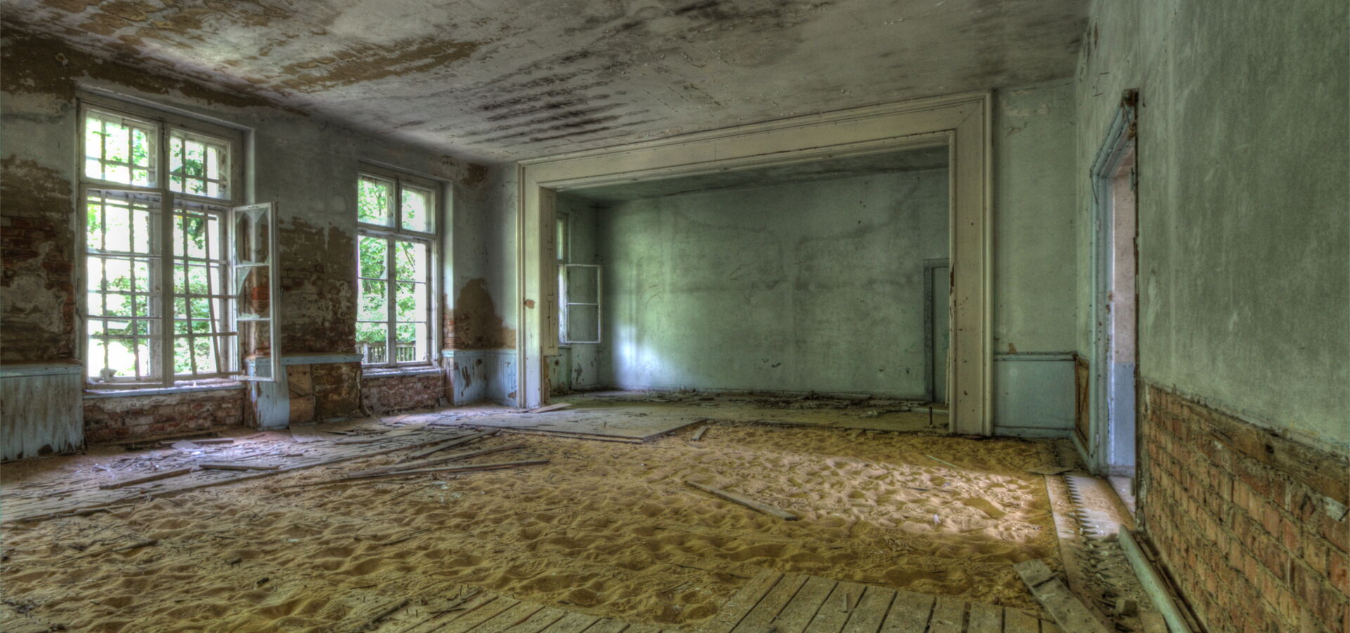 Verlassener Raum mit Sand und alten Fenstern.
